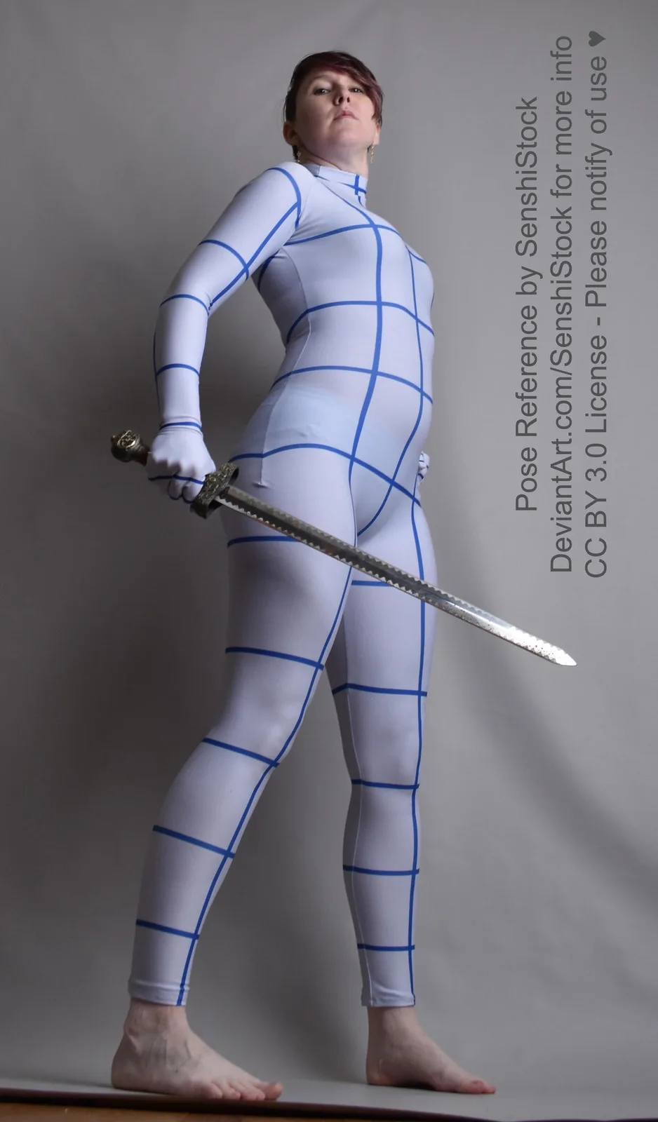 A person in a white, form-fitting bodysuit with blue grid lines stands barefoot, holding a sword in a dynamic pose against a…