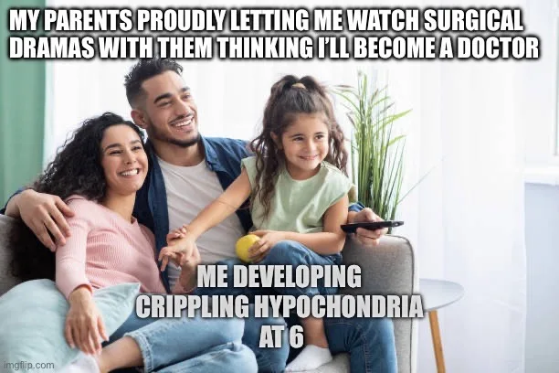 A family of three — a man, a woman, and a young girl — are smiling while sitting on a couch, watching TV. The girl holds a…