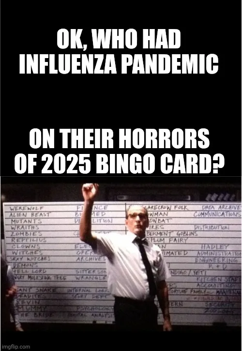 A man in a white shirt and tie stands in front of a large whiteboard filled with horror-themed bingo squares like…