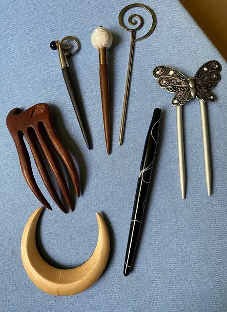 A flat-lay photo shows several decorative pens and writing tools on a blue fabric surface, including a wooden comb, a…