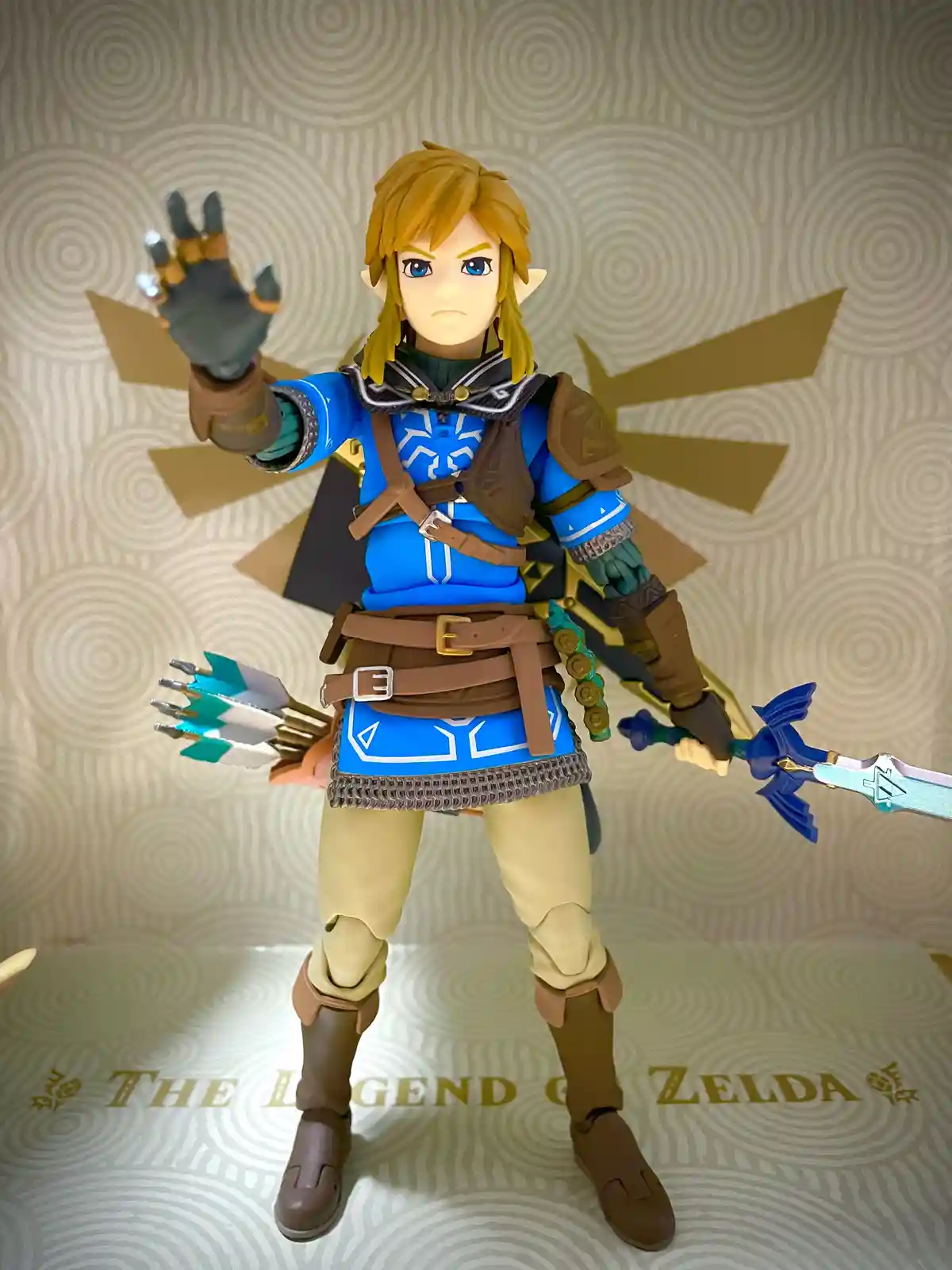 A figurine of Link from The Legend of Zelda, posed with a sword in one hand and a shield in the other, standing in front of…
