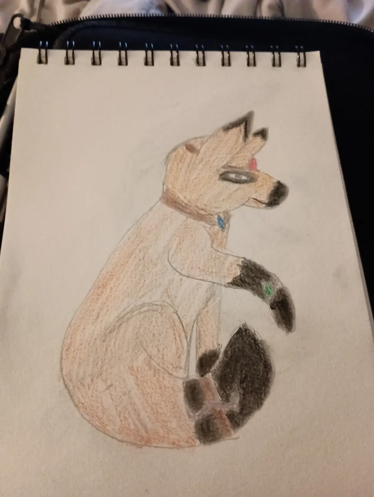 A hand-drawn colored pencil illustration of a stylized fox sitting upright on a spiral-bound notebook page, featuring a red…