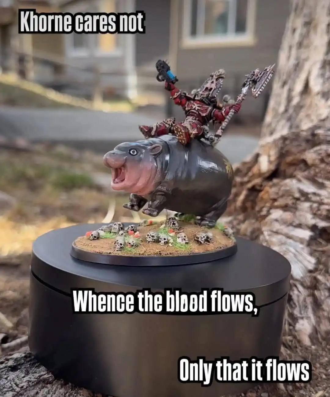 A painted miniature of a red-armored warrior riding a hippopotamus-like creature, both mounted on a circular base with…