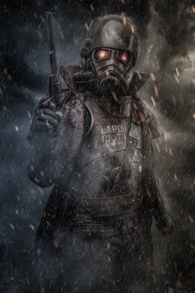 A heavily armored, masked figure in a dark, rainy, and smoky environment holds a pistol. The figure wears a gas mask with…