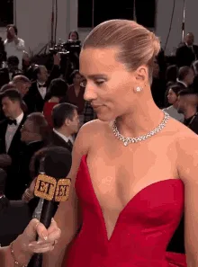 A six-panel image sequence shows actress Scarlett Johansson at a red carpet event, wearing a red strapless gown and diamond…