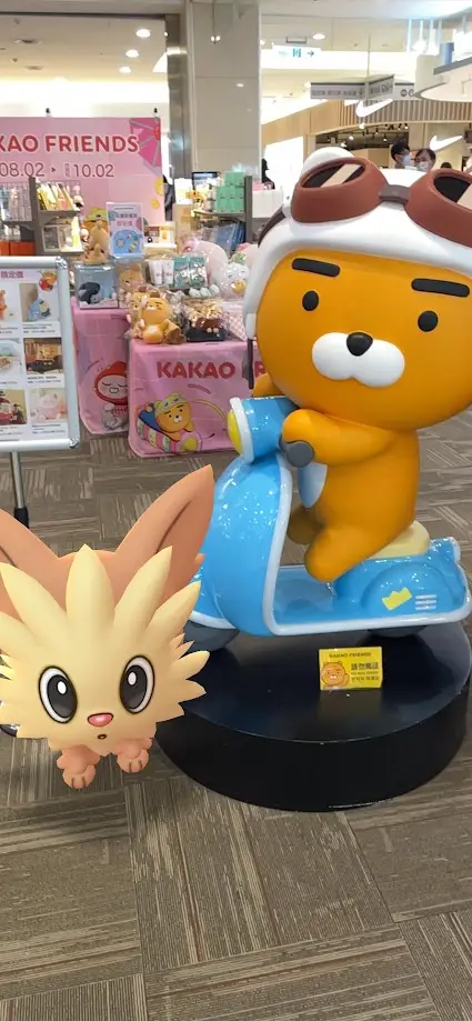 A large orange cartoon bear statue wearing a white helmet with brown goggles, riding a blue scooter on a black pedestal in a…