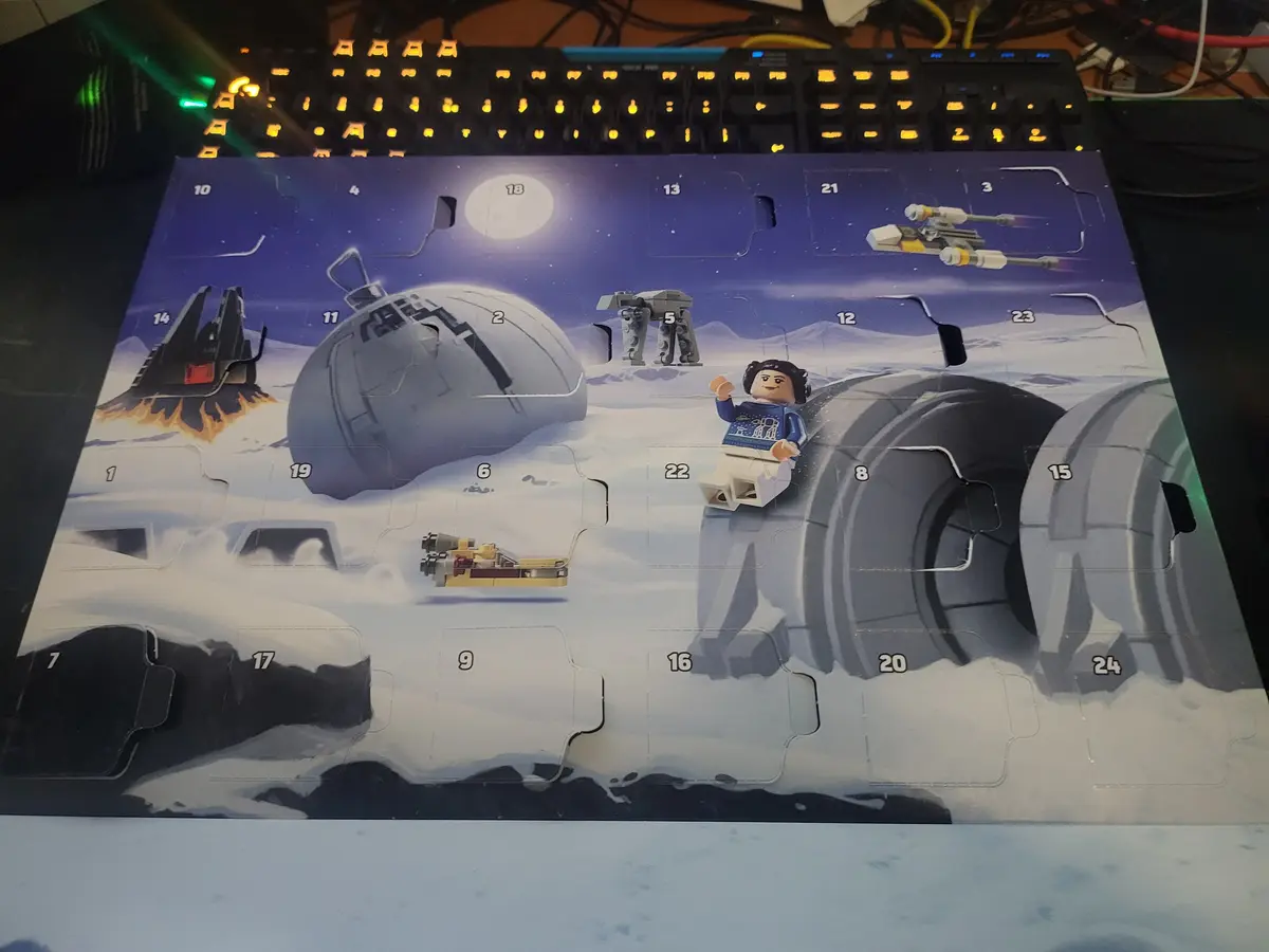 A Lego Star Wars Advent calendar featuring a snowy Hoth scene with numbered flaps, showing a Lego figure of Princess Leia…