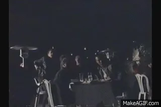 A six-panel GIF compilation from a dark, gritty movie scene showing a group of people at a dinner table, a man pointing a…