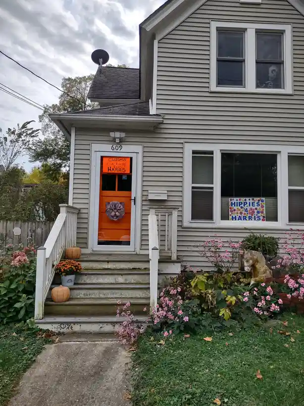 A house with an orange front door decorated with a cat face cutout and an orange sign reading 'Childless Cat Lady for…
