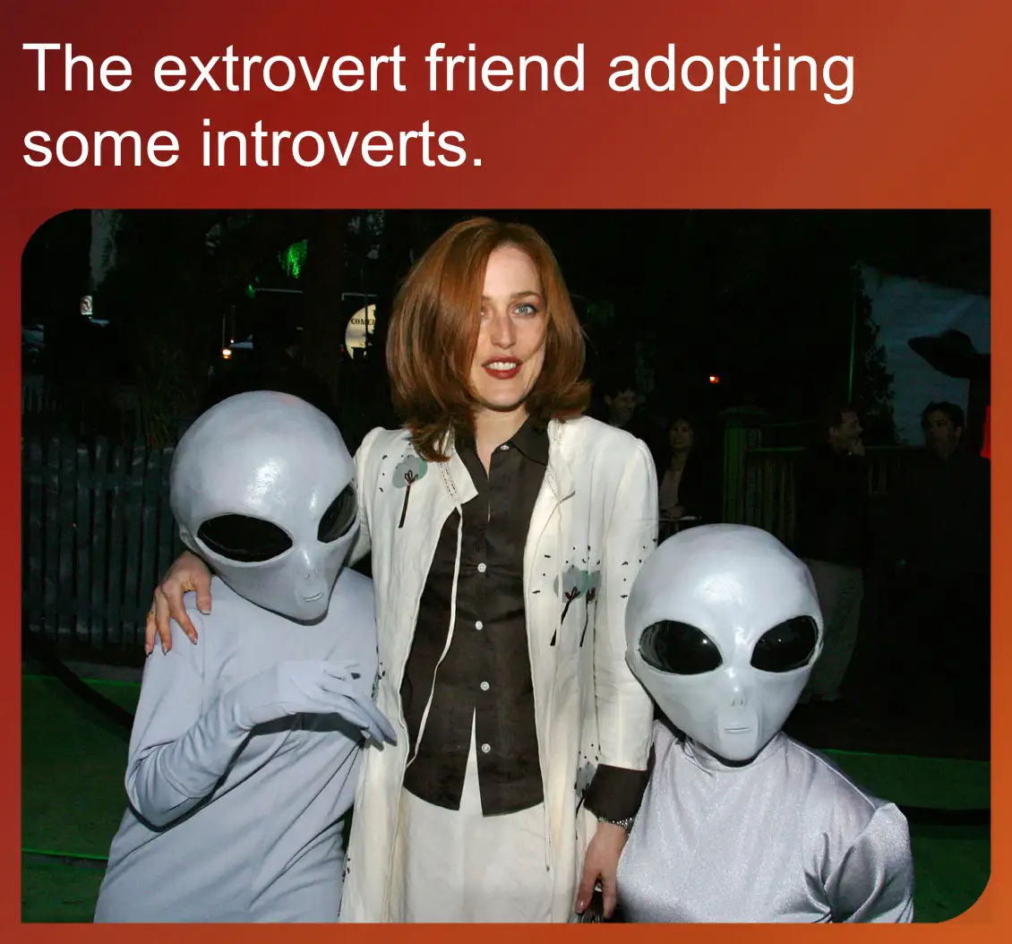 A woman with reddish-brown hair and a white jacket stands between two people in full alien costumes, both wearing white…