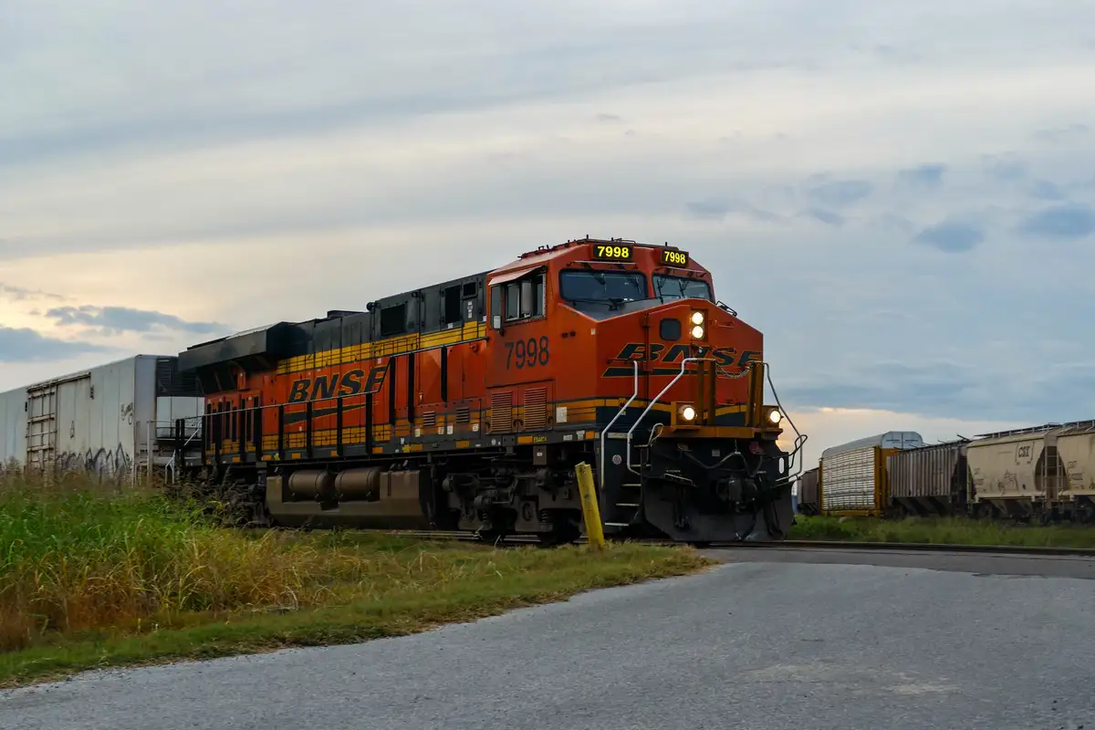 A BNSF locomotive numbered 7998 is shown on a railway track, with the number 7998 displayed prominently on its front and…