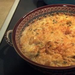 a close-up photo of a baked casserole in a decorative ceramic baking dish with a brown rim and patterned border, showing a…