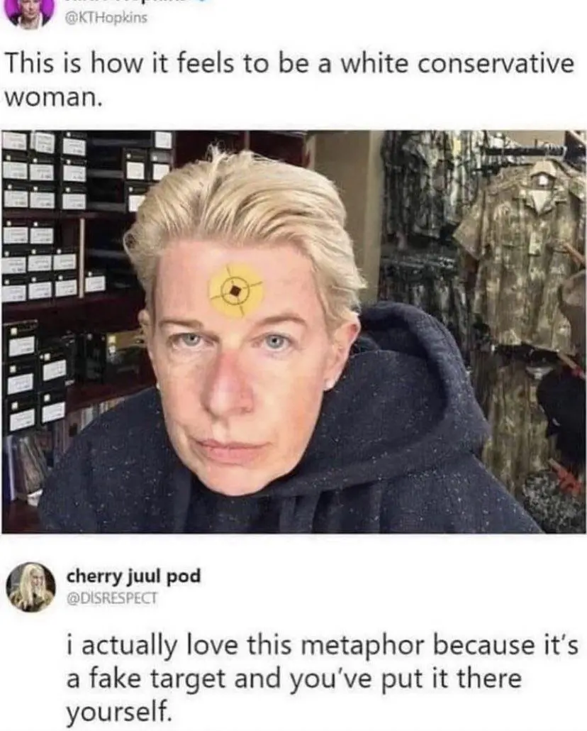 A woman with short blonde hair and a dark hoodie has a yellow bullseye drawn on her forehead. The image is framed as a…