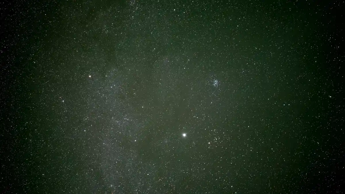 A dark, star-filled night sky with numerous bright and dim stars scattered across a greenish-black background. The overlaid…