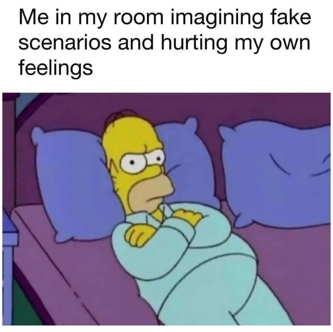 The image shows Homer Simpson lying in bed under a light blue blanket, looking sad and thoughtful with his arms crossed over…