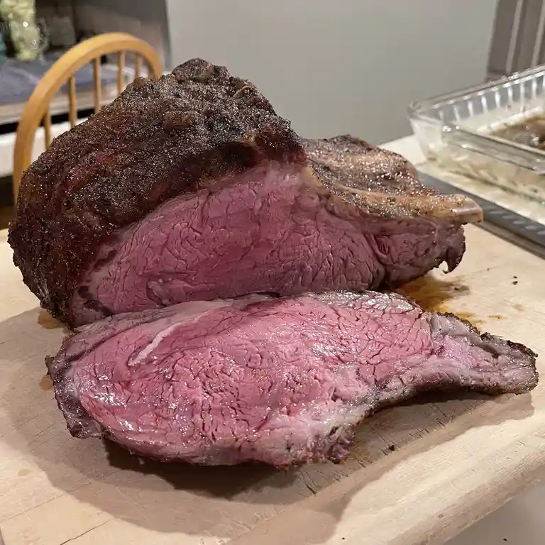 A large, sliced roast beef with a dark seared crust and pink, juicy interior sits on a wooden cutting board. In the…