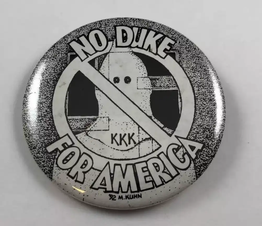 A black and white circular pin features a stylized ghost-like figure with 'KKK' written on its chest, crossed out by a…