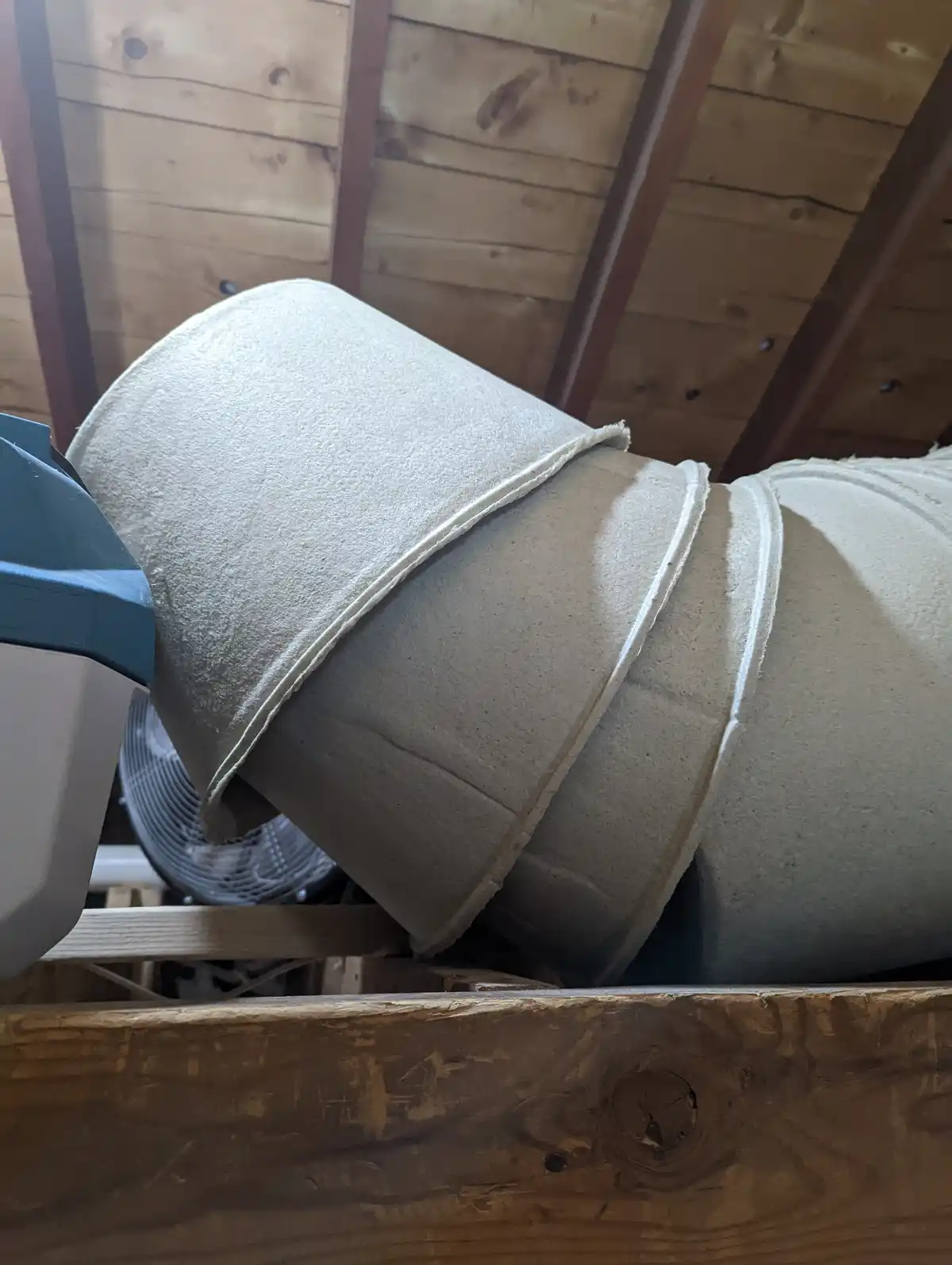 A close-up photo shows large, beige, cylindrical rolls of insulation material lying on their sides in what appears to be an…