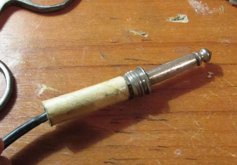 A close-up photo shows a spark plug with its ceramic insulator wrapped in what appears to be a used toilet paper roll…