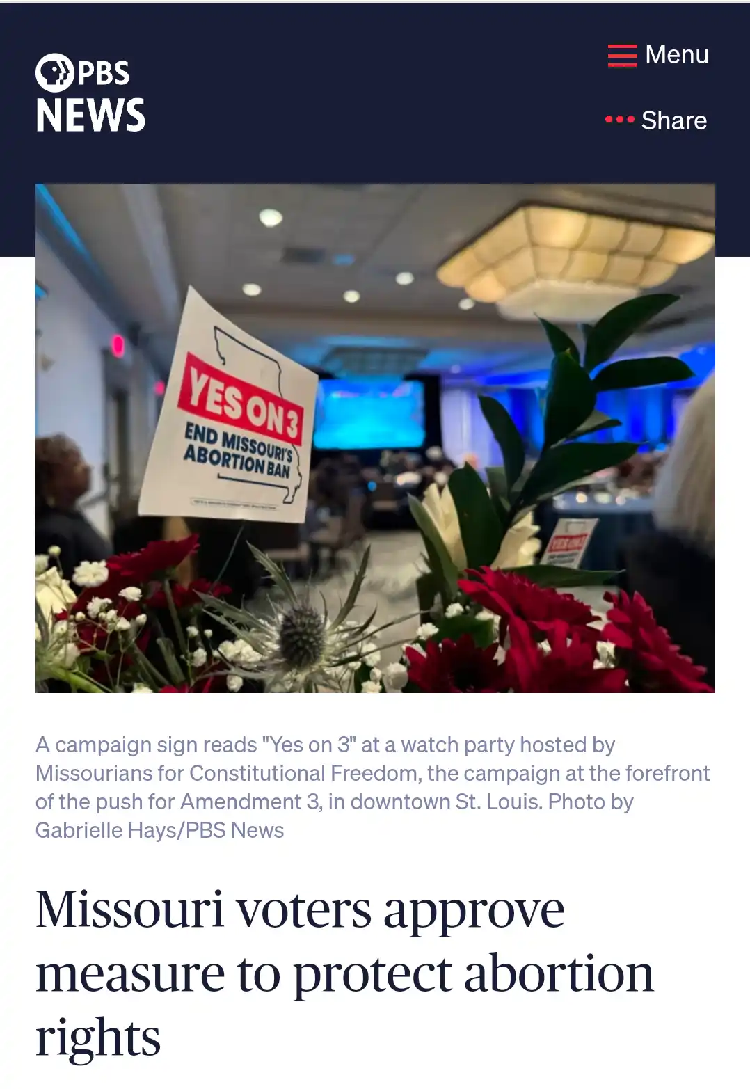A close-up photo shows a white campaign sign with red and blue text reading 'YES ON 3 END MISSOURI'S ABORTION BAN' placed in…