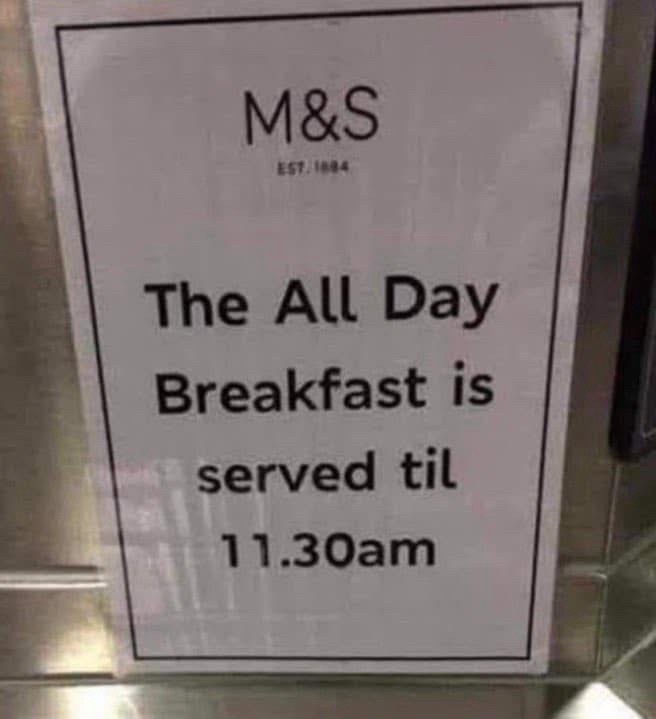 A white sign with black text from M&S (established 1884) states that 'The All Day Breakfast is served til 11.30am'. The sign…