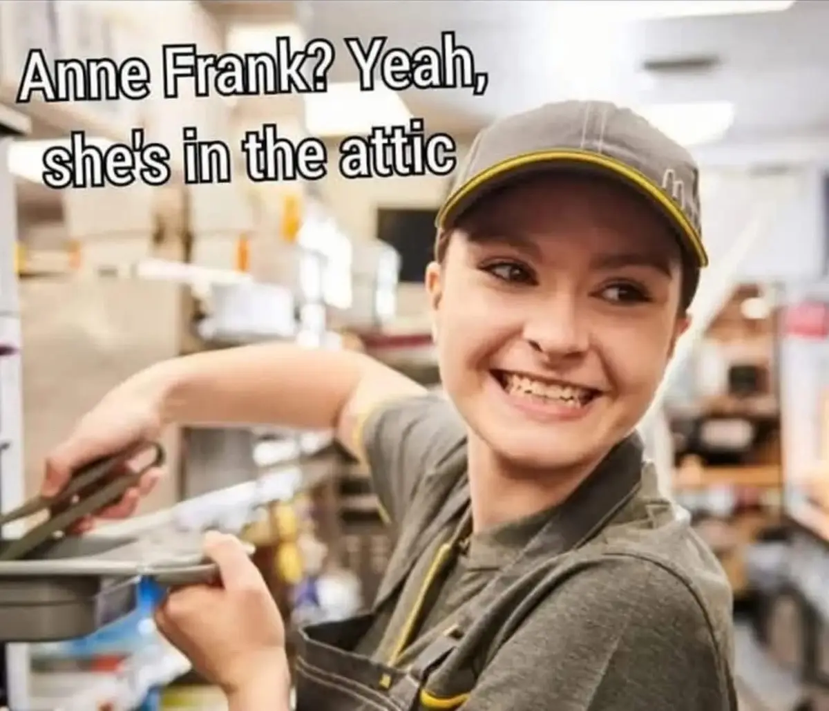 A young woman wearing a grey work cap and overalls smiles while holding a metal pan in a warehouse or storage area. The text…