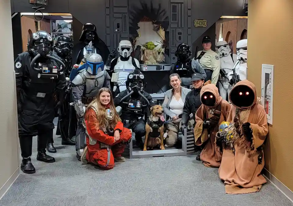 A group photo of people and a dog dressed as Star Wars characters, including Stormtroopers, Darth Vader, Boba Fett, Yoda…