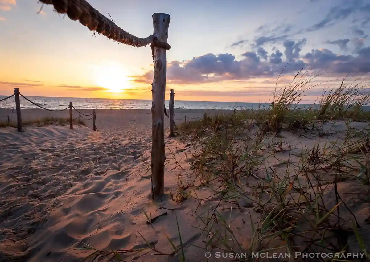A serene beach sunset photo with wooden posts and rope fencing leading to the ocean, overlaid with the text 'i'm not lazy…
