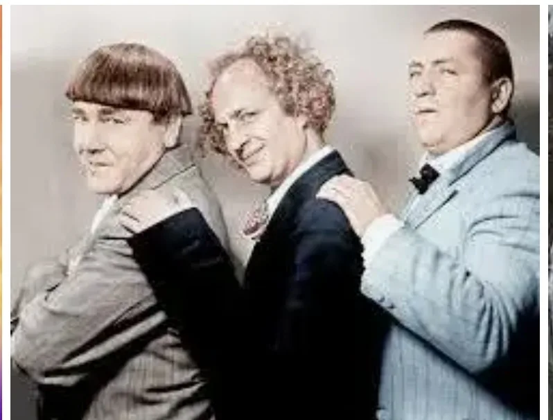 three men in suits stand back-to-back, each with one hand on the shoulder of the person next to them, smiling. the image is…