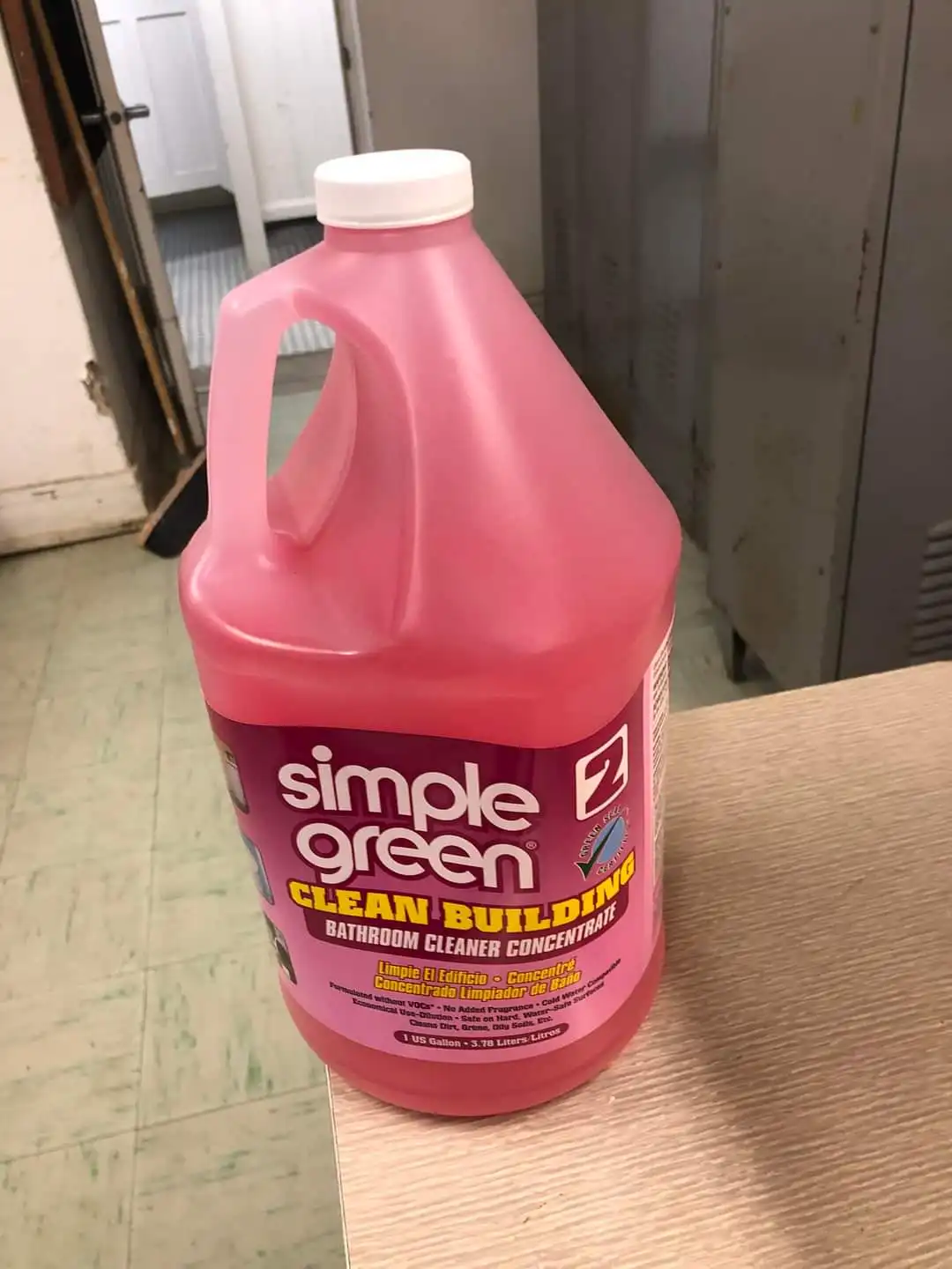 A large pink jug of Simple Green Clean Building Bathroom Cleaner Concentrate sits on a wooden surface, with a white cap and…