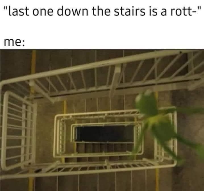 A green puppet, resembling Kermit the Frog, is shown from above, falling down a set of metal stairs while riding a shopping…