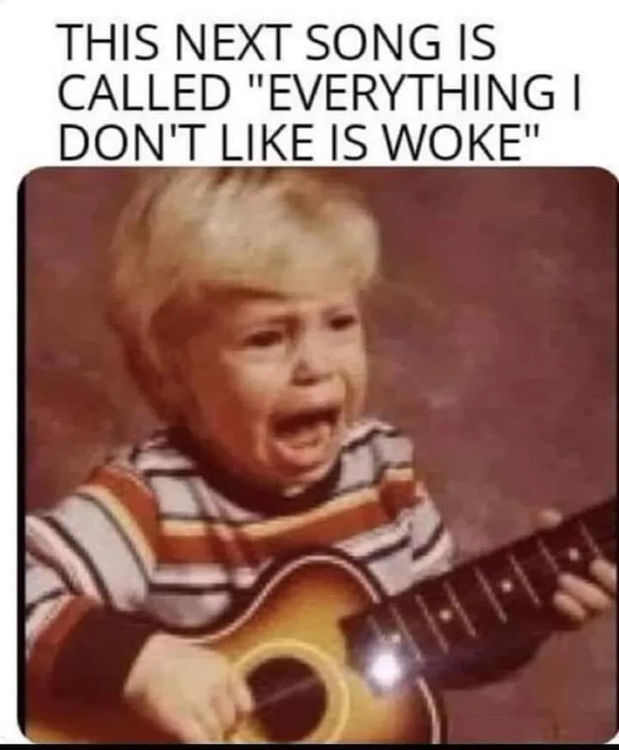 A vintage photo shows a young blonde child in a striped shirt crying loudly while holding a small acoustic guitar. The…