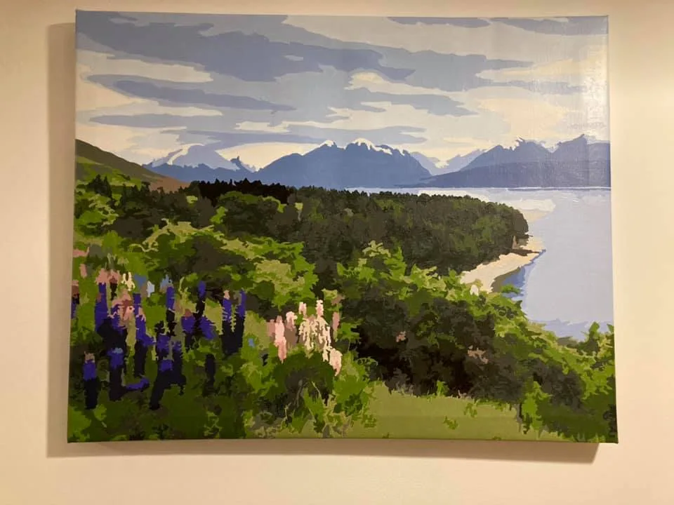 A painting of a scenic landscape with green hills, purple and pink flowers in the foreground, a body of water, and…