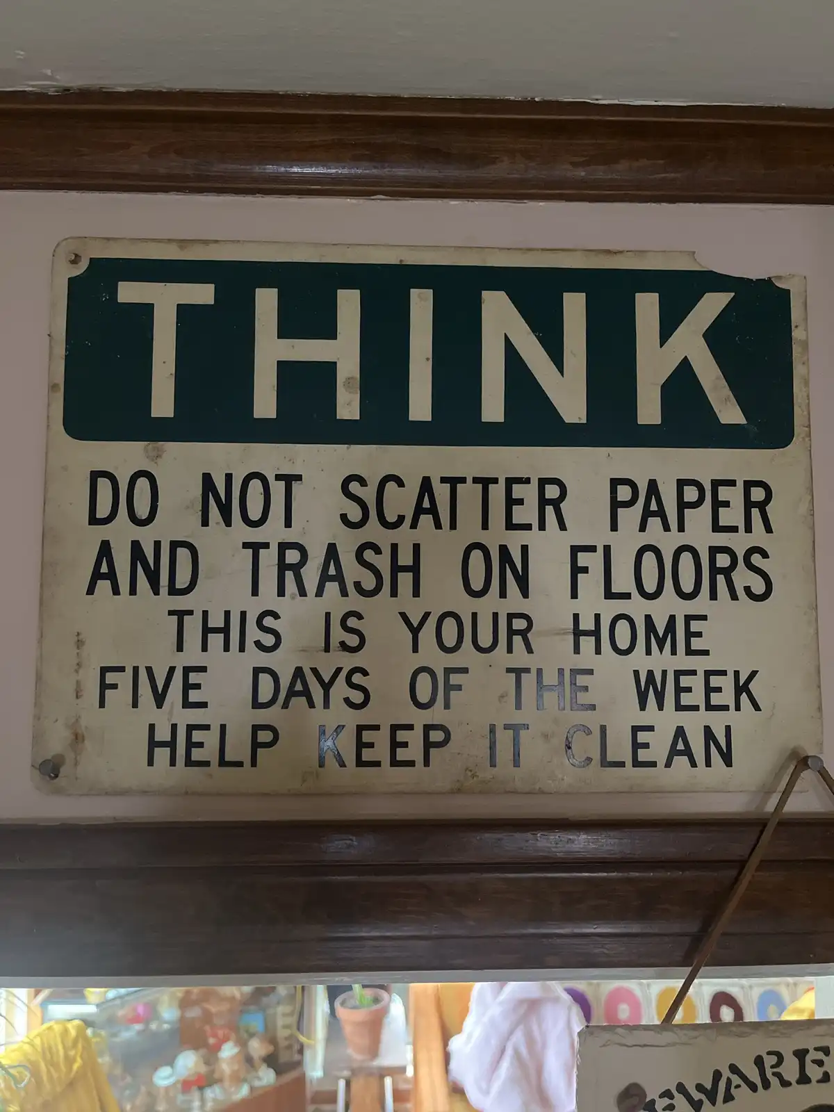 A weathered, vintage-style sign with a green header reading 'THINK' and black text below urging people not to scatter paper…