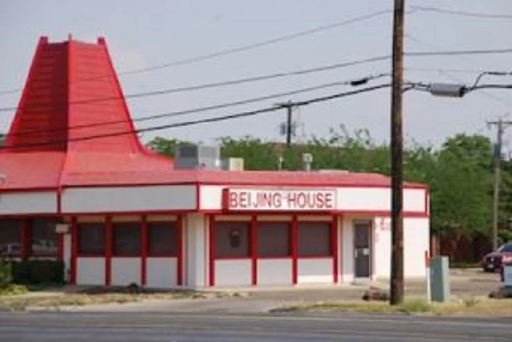 A red and white restaurant building with a distinctive red roof shaped like a pagoda, featuring a sign that reads 'BEIJING…