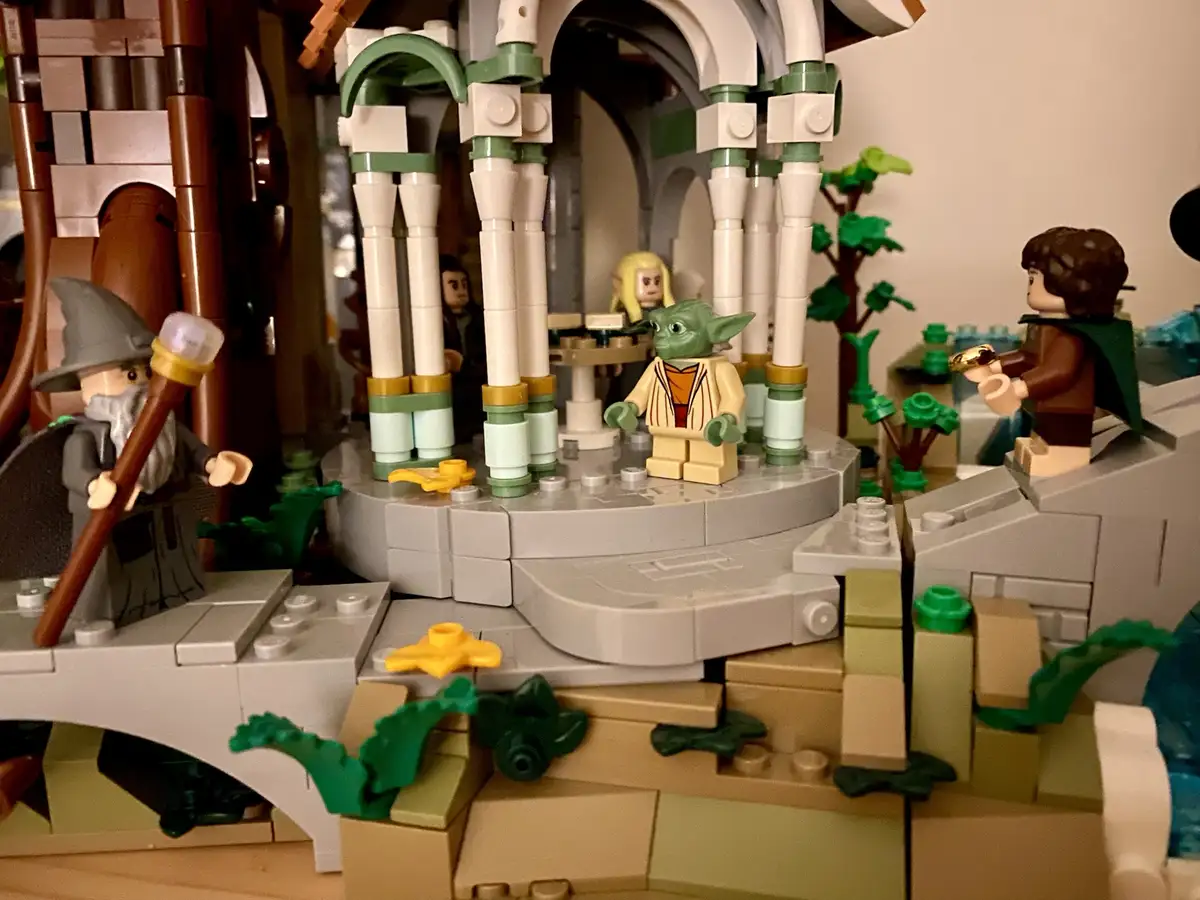 A LEGO diorama featuring characters from The Lord of the Rings and Star Wars, with a LEGO Yoda minifigure standing on a…