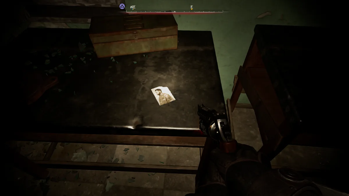 A first-person view from a video game shows a gloved hand holding a revolver, aimed at a small, faded photograph of a man…