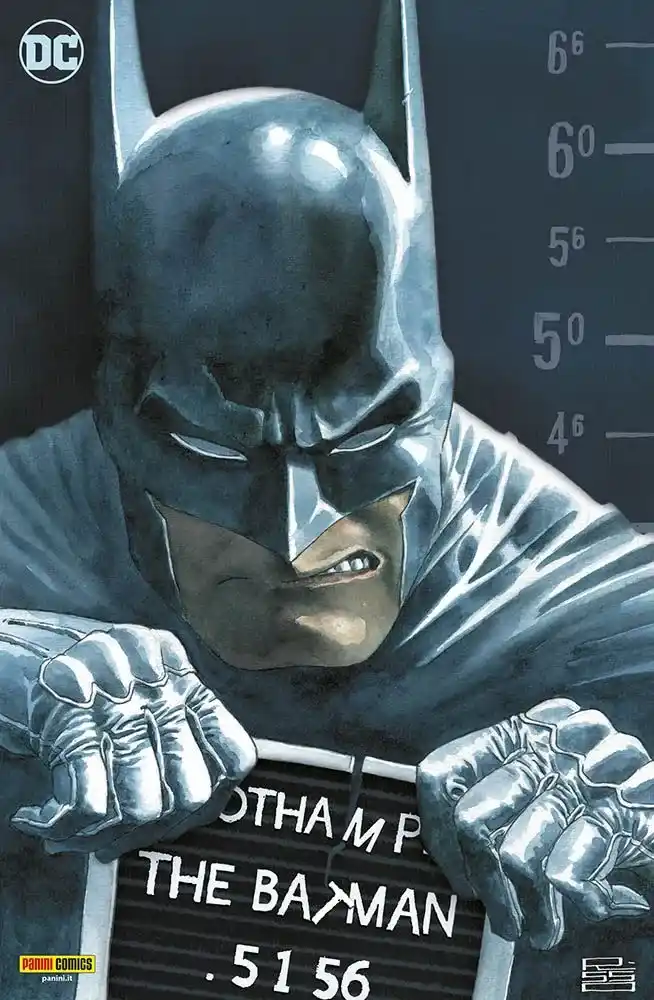 Batman is depicted in a mugshot-style photo, gripping a sign that reads 'THE BAMAN' with his fists, standing before a height…