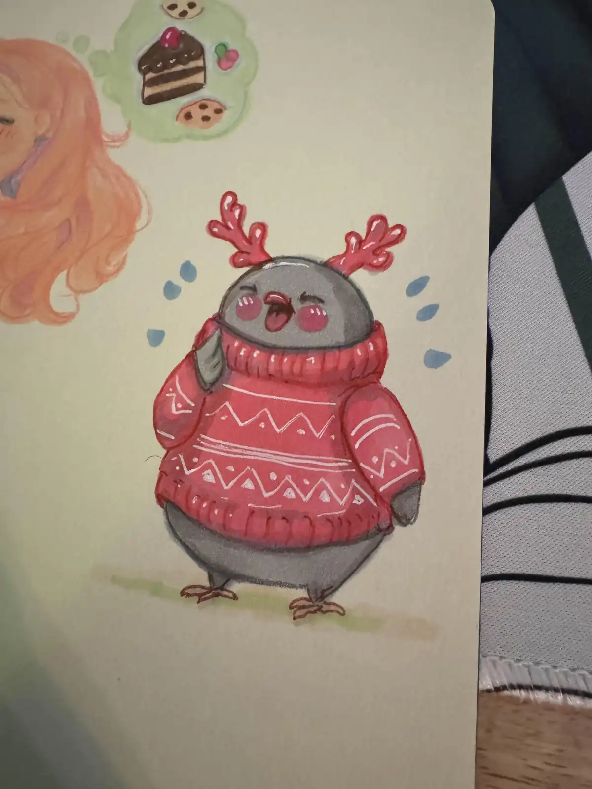 A hand-drawn illustration shows a grey penguin wearing a red holiday sweater with white patterns and red antlers, looking…