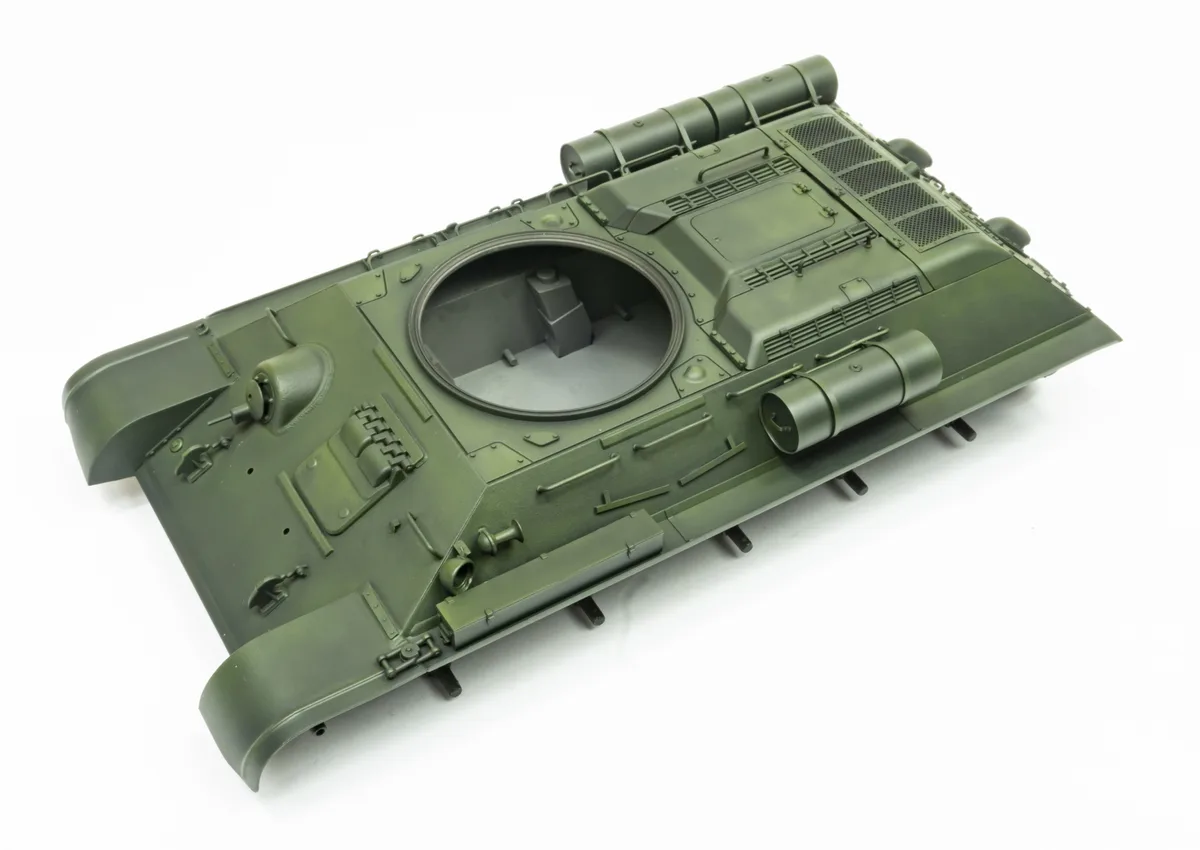 A green plastic model of a tank's hull is shown from above against a white background, with a large circular opening where…