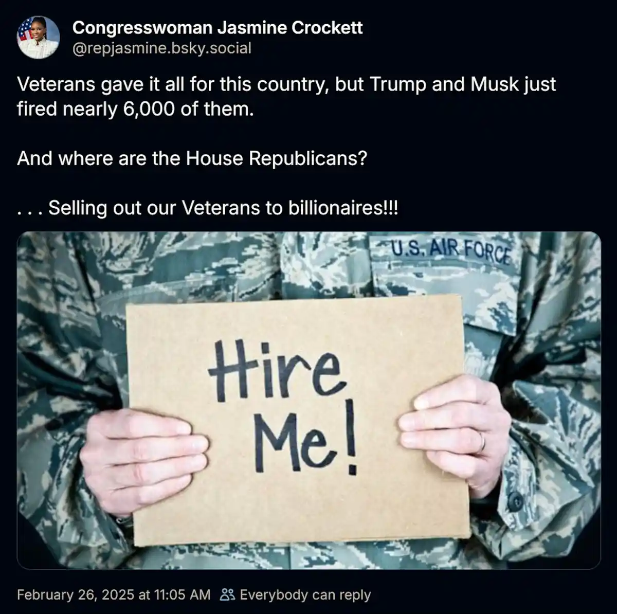 A person in a U.S. Air Force camouflage uniform holds a cardboard sign that reads 'Hire Me!' in handwritten black marker…