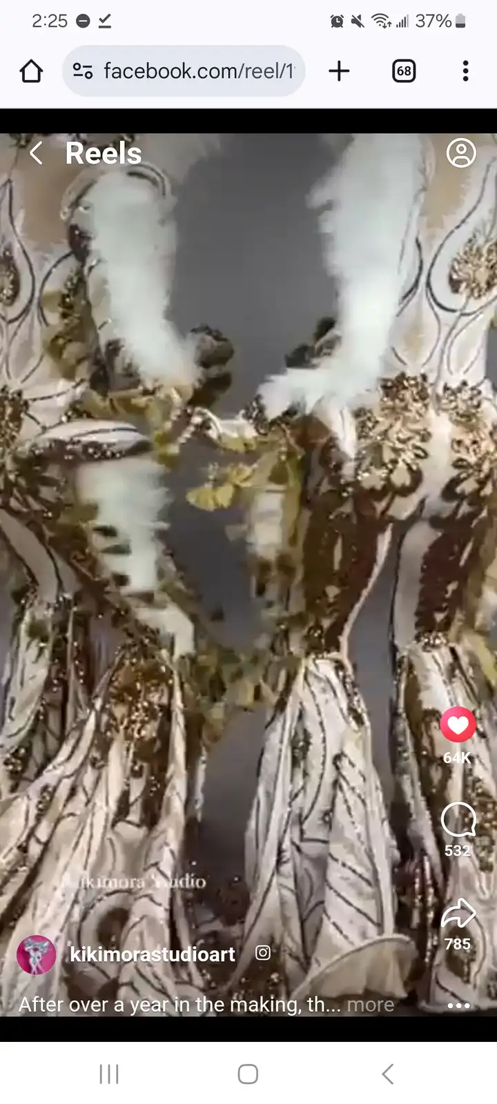 The image shows a close-up of an ornate, heavily embellished costume with white feathers and gold embroidery, appearing to…