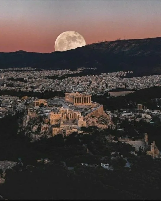 a scenic photo of the acropolis of athens at dusk, with the parthenon prominently featured on a hill overlooking the city. a…