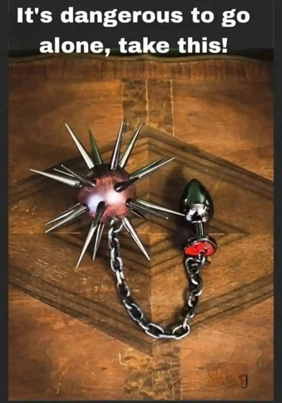A spiked ball and chain toy and a butt plug are chained together and placed on a wooden surface. The overlaid text reads…