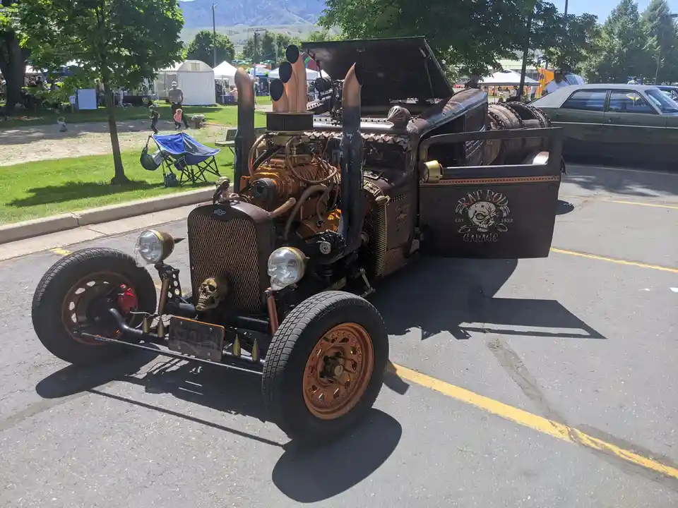 A heavily customized rat rod hot rod with exposed engine, skull-themed headlights, and a 'GENUINE STOLEN' license plate is…