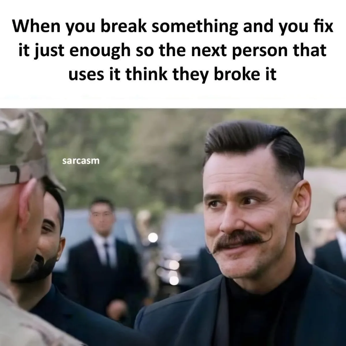 A man with a mustache and slicked-back hair, wearing a black suit and turtleneck, looks sideways with a smug, sarcastic…