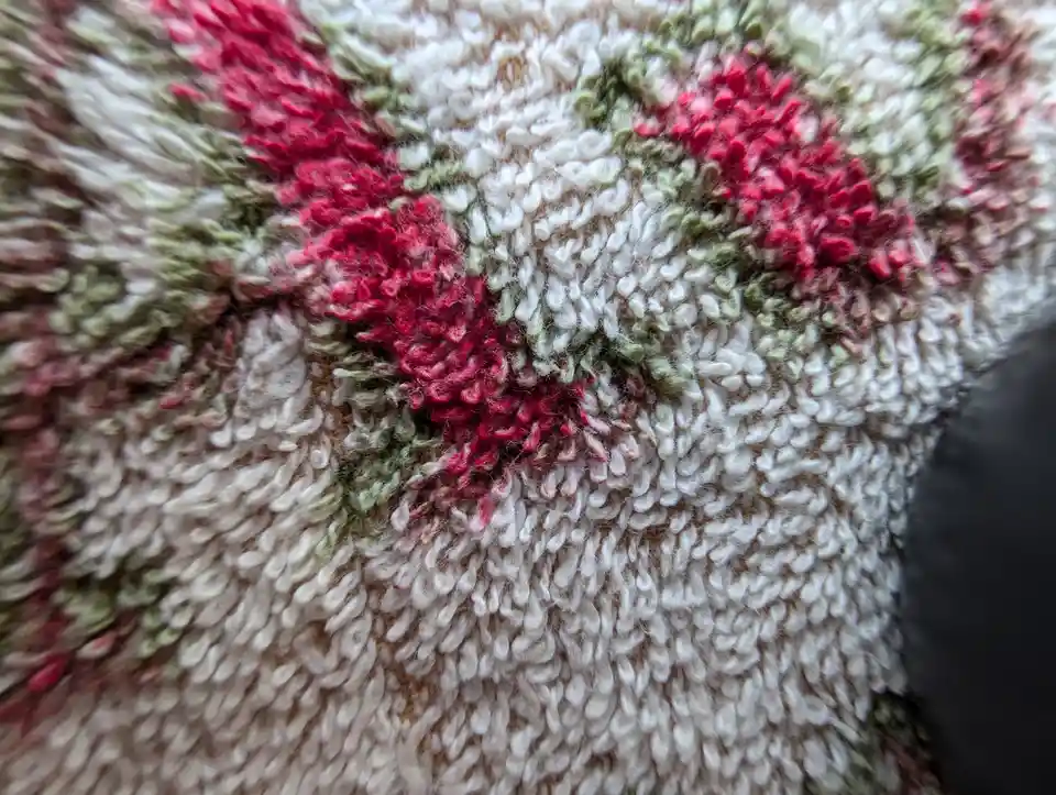 A close-up photo of a textured, shaggy rug with a floral pattern in red, green, and white yarn. The overlaid text reads 'i'm…