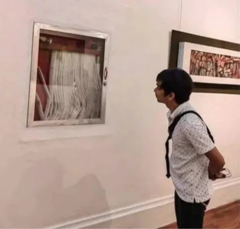a man in a patterned shirt and backpack stands in an art gallery, looking at a framed piece that appears to be a simple…