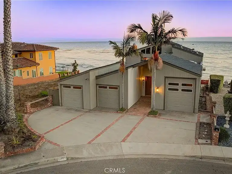 a modern coastal house with three visible garage doors, set against a sunset ocean view with palm trees, overlaid with the…