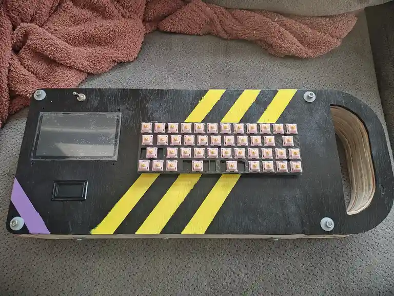 A custom-built keyboard with pink keycaps is mounted on a black wooden board painted with yellow and black hazard stripes…
